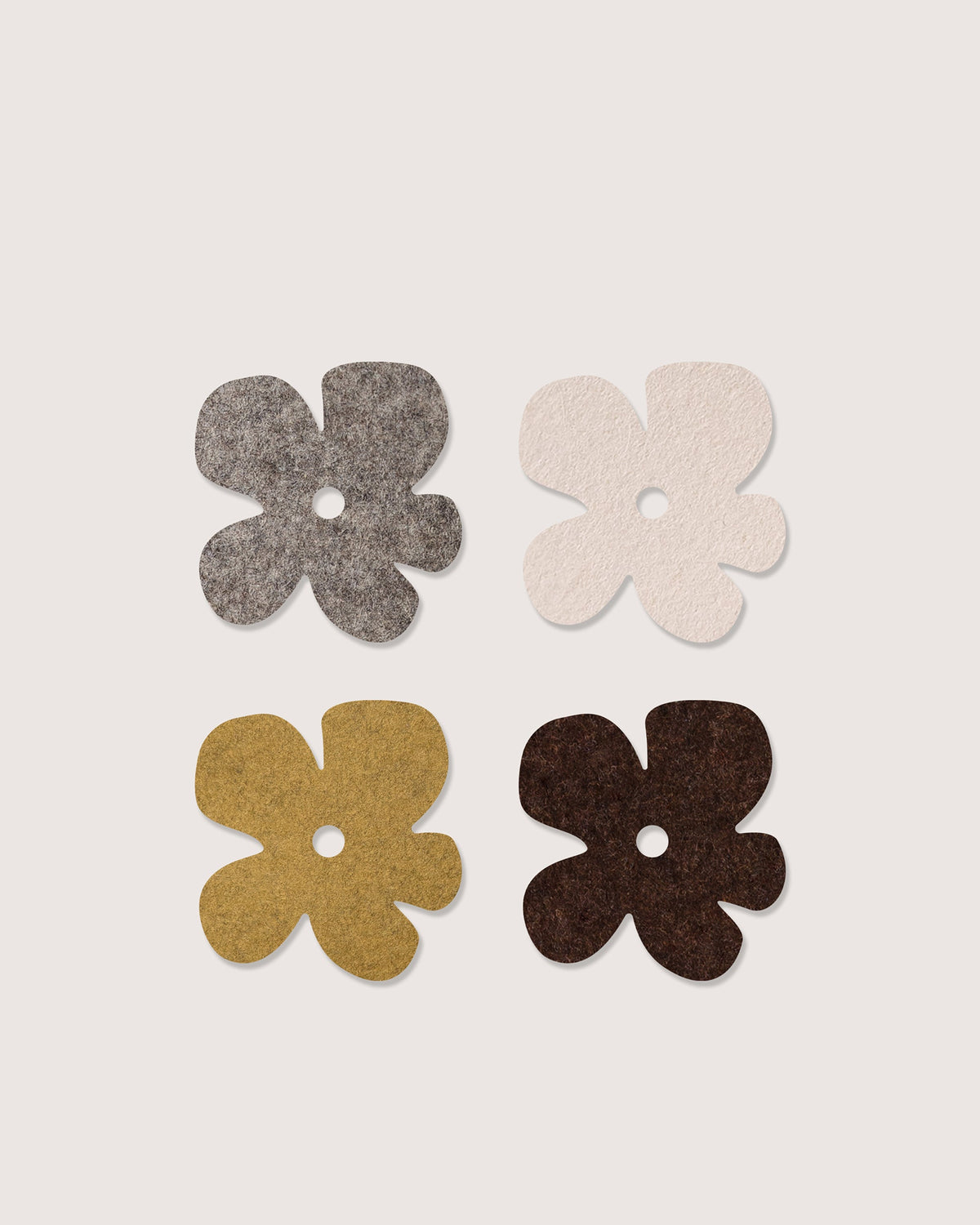 Four flower-shaped Merino wool felt coasters in brown, cream, ochre and chocolate